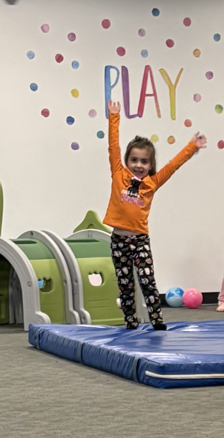 A child cheering on the mats in the indoor gym at Mountainside Children's Center
